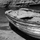 Black and white rowing boat next to a stone beach